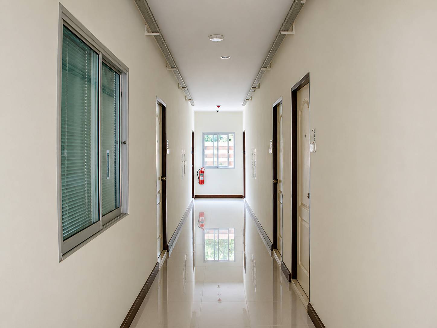 Guest room corridor at Thani Residence, polished tiles and daylight from the end window